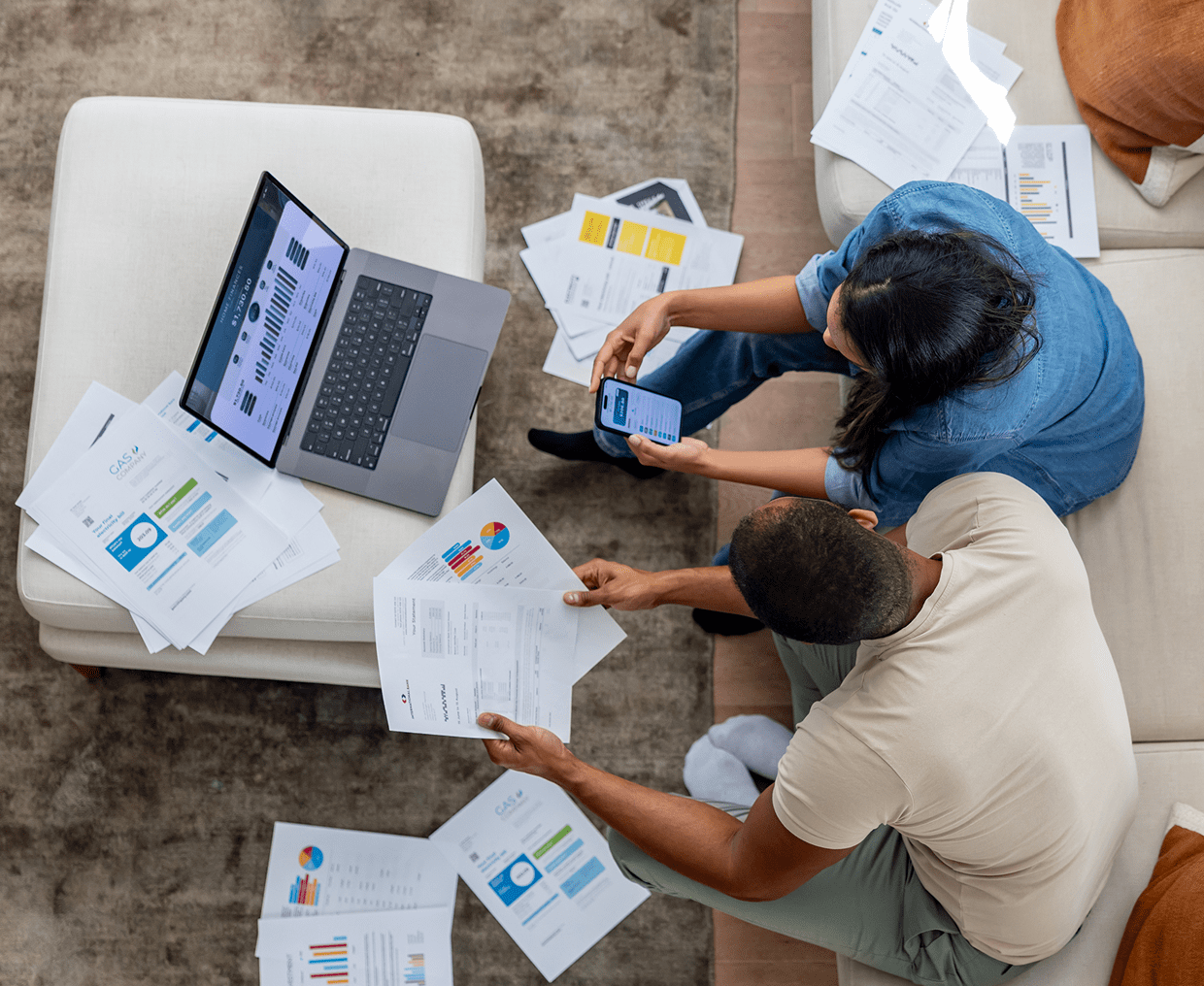 Two people reviewing documents and using devices.