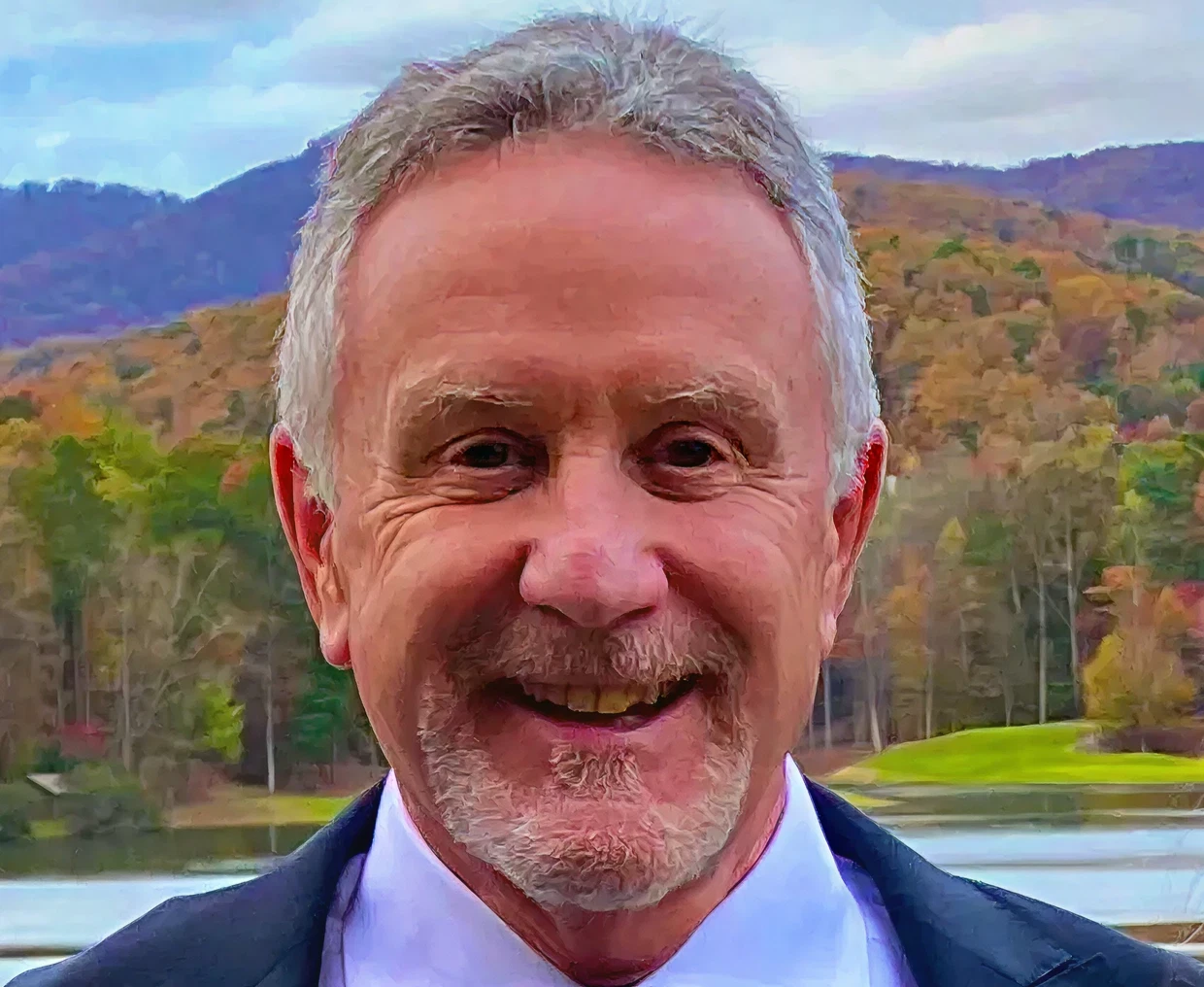 Smiling man outdoors with scenic background.
