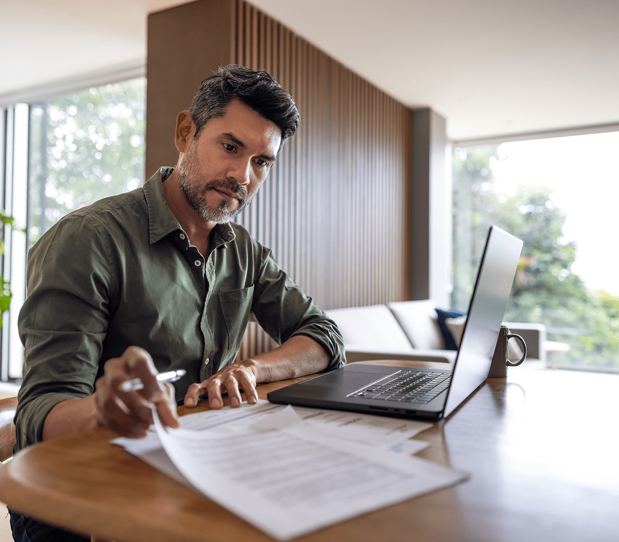 Man working at home with laptop and documents.